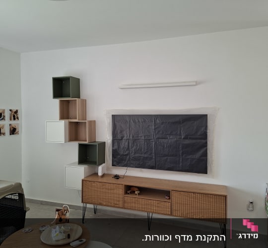 מדף עץ מותקן על קיר עם רהיטים נוספים בחדר